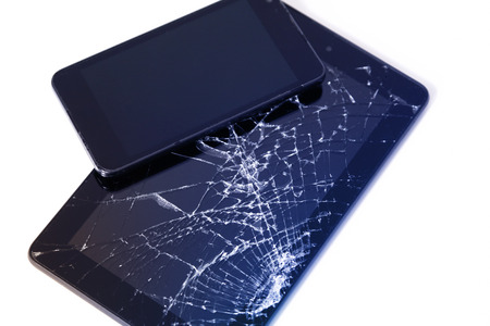 Photos of cracked display on a tablet and black cellphone isolated on white. Tablet with damaged screen.の写真素材