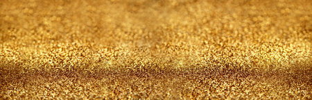 Gold glitter texture sparkling paper background. Abstract twinkled golden glittering background  with bokeh, defocused lights for Christmas holiday bannerの写真素材