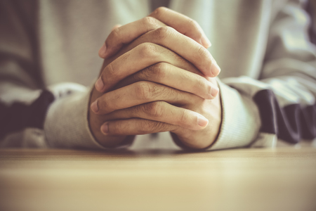 Man praying on a wooden tableの写真素材