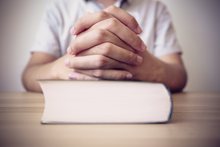 Praying on a wooden table with a Bible