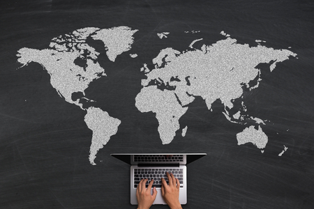 Global Business concept with hands typing laptop on the blackboard background.の写真素材