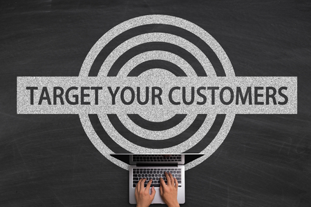 Target Your Customers concept with hands typing laptop on the blackboard background.の写真素材