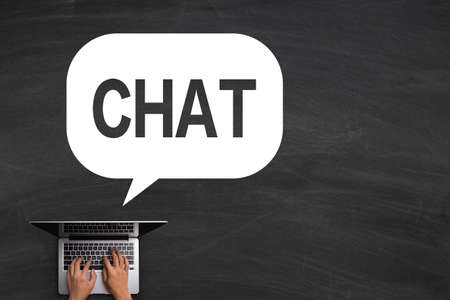 Chat speech bubble with hand playing laptop on the blackboard.の写真素材