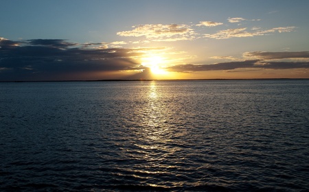  Golden sunset over sparkling water with blue sky.の写真素材