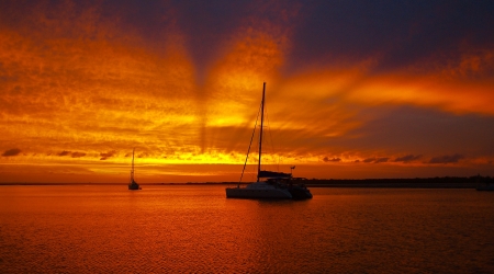 Rays at Dusk - Sunset   Outstanding gold yellow rayed sunset over sailboat with ocean water reflections の写真素材