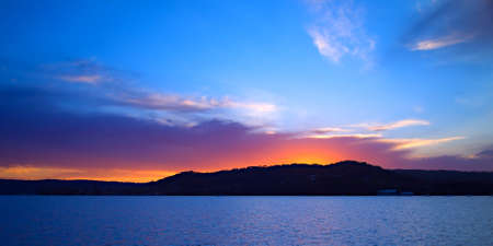 Vivid crimson and blue seascape waterscape sunset, over Saratoga, with water reflections. 
Captured on Brisbane Water, Gosford, Central Coast, New South Wales, Australia.の写真素材