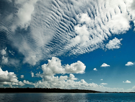 A spectacular inspirational brightly coloured cloudy sea water tropical seascape featuring  white Altocumulus cloud formation (AKA. Mackerel Sky) in a blue sky with ocean water reflections. Australia.の写真素材