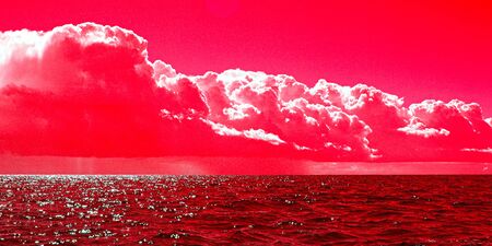 A spectacular inspirational brightly coloured cloudy Cumulonimbus sea water tropical panoramic sunrise seascape featuring silhouettes with ocean water reflections, Australia.の写真素材