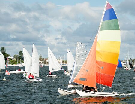 Racing Cat sailboat closeup with a bright multicoloured sail competing in a junior sailing regatta. Australia. Commercial use photo. Teamwork by young sailors. Lake Macquarie, Australia. Photo for commercial use.の写真素材
