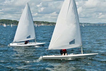 Children sailing in small colourful boats and dinghies for fun and in competition. Teamwork by junior sailors racing on saltwater Lake Macquarie. Photo for commercial use.の写真素材