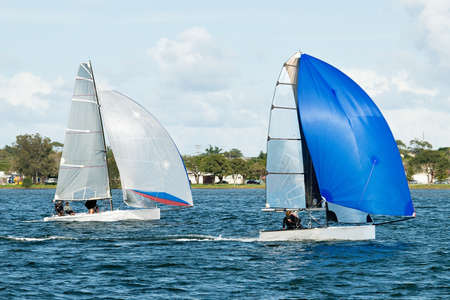 Children sailing in small colourful boats and dinghies in competition. Teamwork by junior sailors racing on saltwater Lake Macquarie. Photo for commercial use.の写真素材
