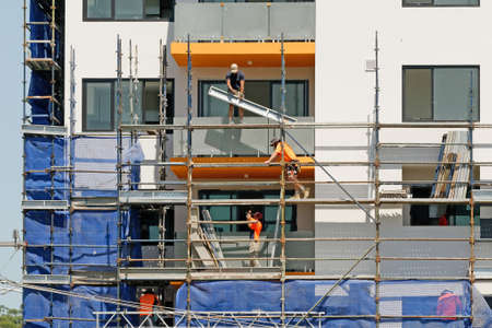 Gosford, New South Wales, Australia - March 4, 2019: Workers disassembling scaffolding and removing...
