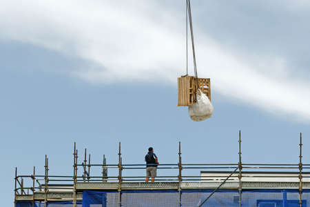 Gosford, New South Wales, Australia - January 31, 2019:  A working tower crane lifting a load with a...