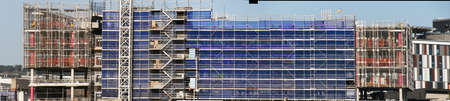 Construction work progress on the new hospital building site with blue sky and installed blue safety netting.の写真素材