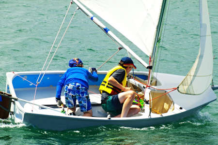 Two Boys sailing in a dinghy for fun and competition. Teamwork by junior sailors racing on salt water Lake Macquarie, Australia.の写真素材
