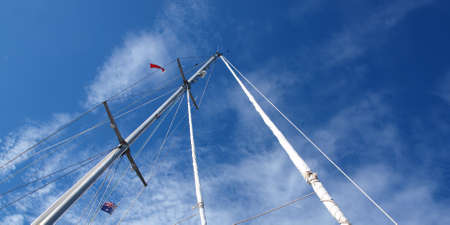 A beautiful nautical sky cloudscape scene, over a yacht mast and rigging, with white Stratocumulus cloud formation in a light  light sky. Beauty in nature image. NSW, Australia.の写真素材