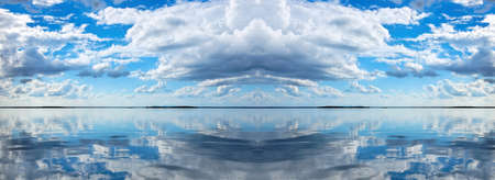 Nephology at its best. A beautiful meteorological sky cloudscape scene, with white Cumulus cloud formation in a mid blue sky over ocean water with reflections. Seascape beauty in nature. New South Wales, Australia.の写真素材