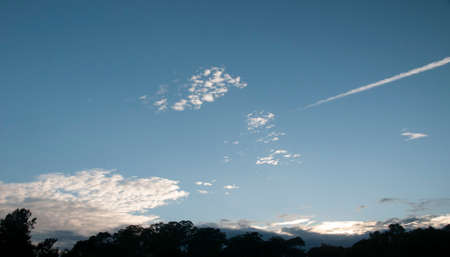 Nephology at its best. Mixed cloud type image. White Altostratus, Nimbocumulus and Vapour trail cloud in blue sky. Atmospheric beauty in nature. New South Wales, Australia.の写真素材