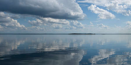 Natural atmospheric photography. A beautiful meteorological sky cloudscape scene, with white Cumulus cloud formation in a mid blue sky with ocean water reflection. New South Wales, Australia.の写真素材