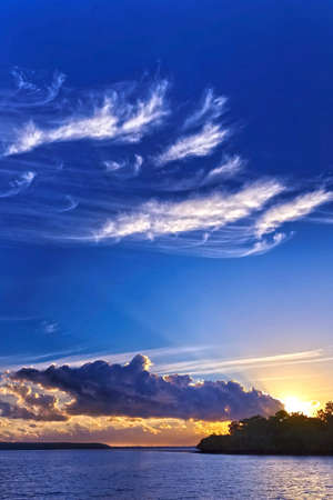 Sunrise seascape with vivid blue sky and white wispy  clouds over ocean.の写真素材