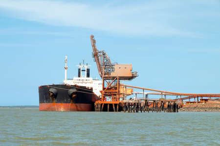A 254 meter Ore Carrier Cargo Ship unloading Bauxite at a Gladstone Harbour wharf, Queensland, Australia.の写真素材