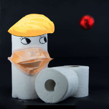 Toilet paper roll with eyes and hair wearing a protective face mask while looking with concern at a red suspended airborne virus ball on black background.の写真素材