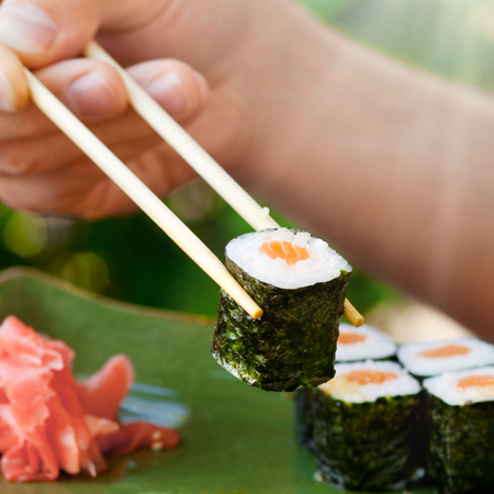 Man's hand holding sushi with chopsticks, Japanese seafoodの写真素材