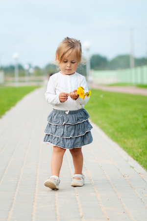 Little girl walking with flowers in hand outdoorsの写真素材