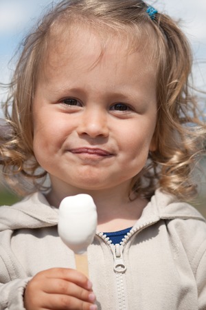 Smiling little child eating ice cream outdoorsの写真素材