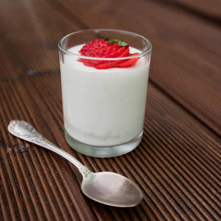 Tasty yoghurt with fresh strawberry over wooden backgroundの写真素材