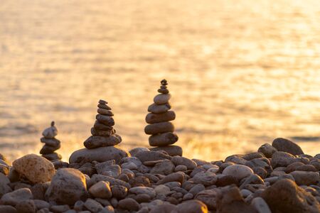 Balanced stone pyramide on shore of the ocean at dawn. Sea pebbles tower closeup symbolizing...
