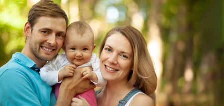Happy family spent time together outdoors. Portrait of mother, father and baby looking at camera. Summer time.の写真素材