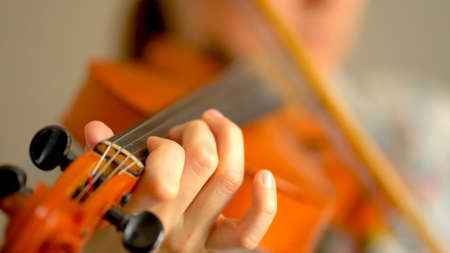 Young woman playing the violin. Hands of musician, close up view. Front view.の写真素材