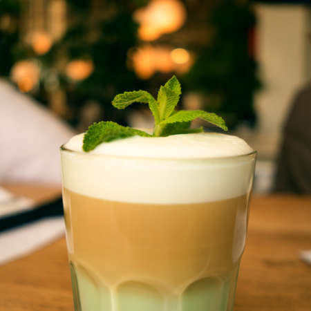 Favourite drink. Raf with milk, syrup, whipped cream and mint leaves. A glass of coffee. Close-up.