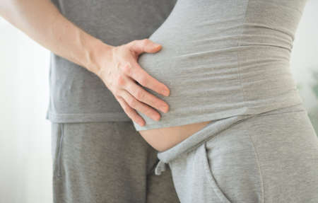 Pregnant woman and her husband holding hand together. Young family is happy in anticipation of a...