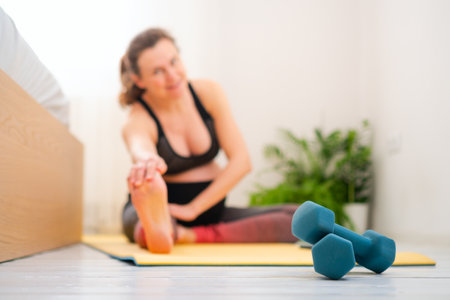 Close-up of dumbbells, pregnant woman training in the background. Light workout during pregnancy.の写真素材