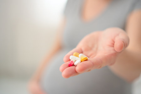 Close-up top view of pregnant woman hand with a pill. Concept of prenatal medication and health monitoring.の写真素材