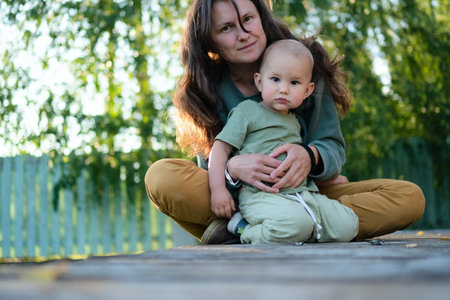 Heartwarming outdoor moment as young mother holds her delighted child. Natural setting enhances their special bond of love and discovery.の写真素材