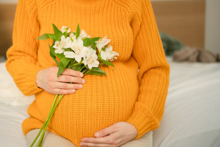 Detailed shot of pregnant womans hands softly stroking her rounded abdomen. Intimate moment of...