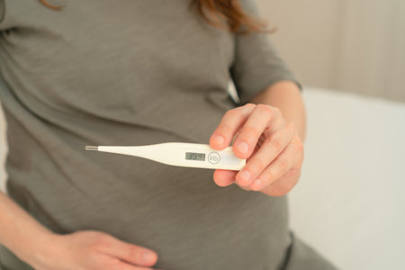 Mom-to-be taking her temperature during pregnancy. Thoughtful moment of self-care and health...