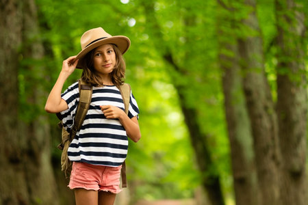 Youthful adventurer pauses mid-trail, glancing back with anticipation. Packed backpack signals beginning of memorable forest exploration in golden sunlight.の写真素材