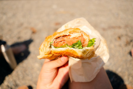 Close-up shot of a croissant with smoked salmon and green lettuce, perfect for healthy snack and outdoor food concepts.の写真素材