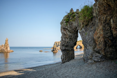 Natural stone arch formation at Cape Ptichiy with breathtaking ocean view under clear blue sky. Ideal for adventure and nature concepts.の写真素材