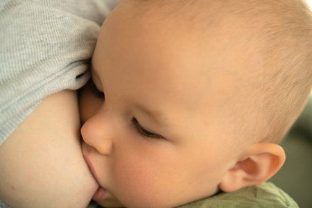 Close-up view of satisfied baby nursing at breast, showing pure contentment. Beautiful example of...