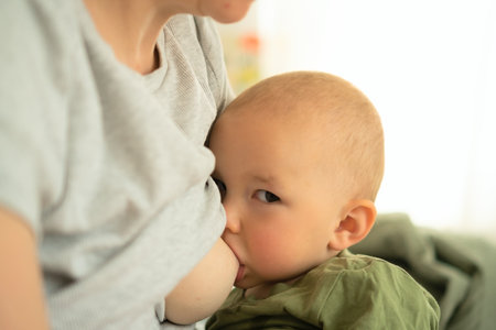 Close-up of happy contented toddler nursing at mothers breast. Natural moment of bonding and nutritious feeding in comfortable embrace.の写真素材