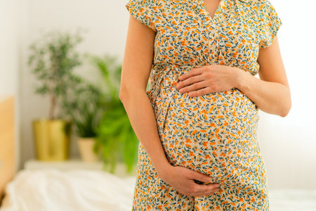 Serene close-up of pregnant womans hands lovingly touching her baby bump. Heartwarming scene of...