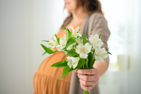 Expecting mother cradling white flowers while lovingly touching her baby bump. Pregnant womanの写真素材
