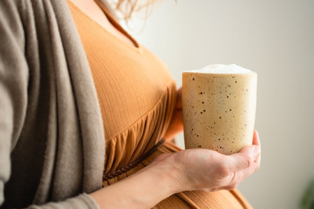 Future mother savoring coffee moment in domestic setting. Balanced view of occasional caffeine indulgence during pregnancy.の写真素材