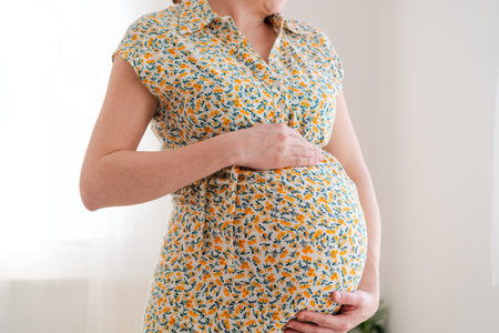 Close-up view of expecting mothers gentle hands caressing her pregnant belly. Quiet domestic scene...