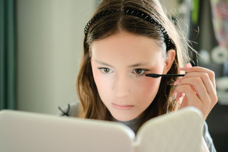 Close-up of a stylish teenage girl applying mascara to her eyelashes by herself. Beautiful young...